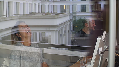 Photo: Kirchhoff: 2 employees laughing at work in the office